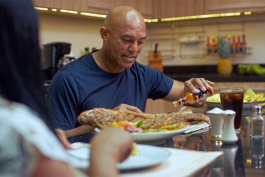 Mo pouring Mo's Heat on seafood at a dining table with people